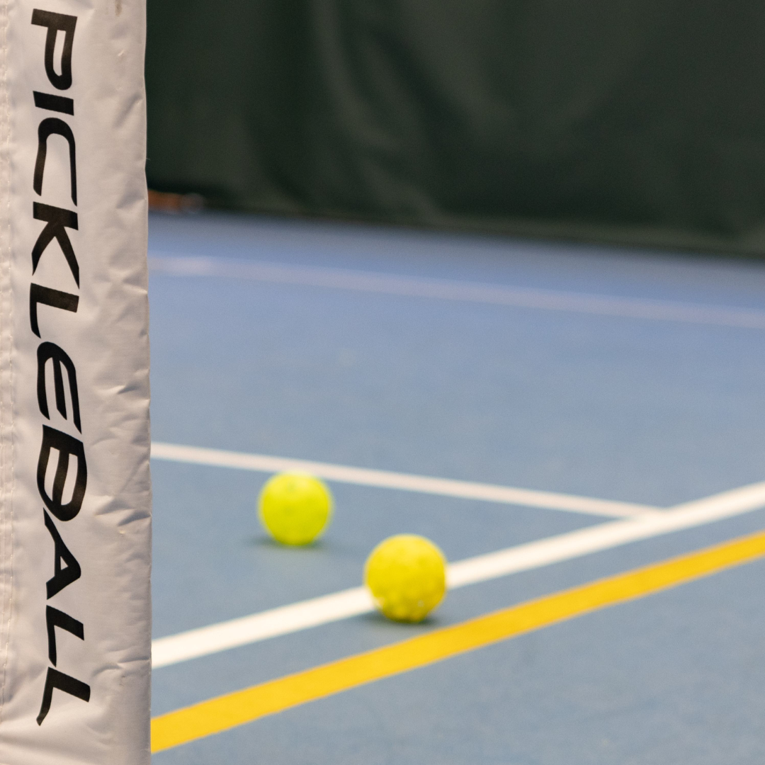 Pickleball court post and yellow pickleballs on blue tennis court with white lines