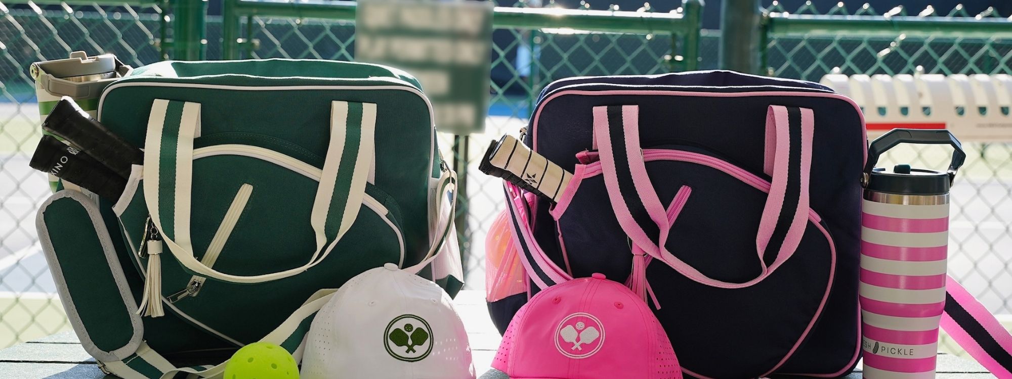 Pickleball bags, hats, paddles, and water bottles on a tennis court bench