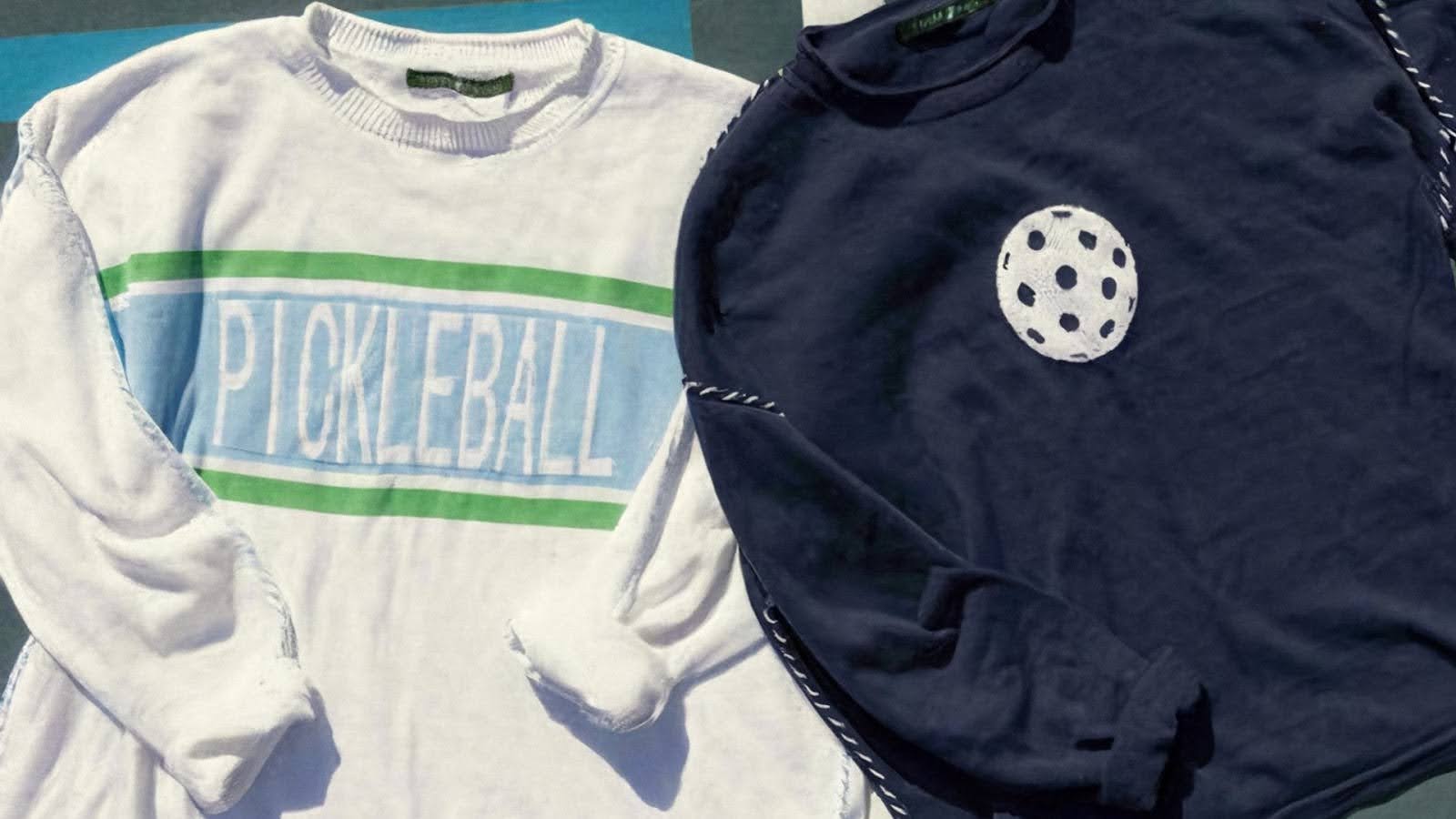 Two pickleball sweatshirts, one white with 'PICKLEBALL' text, one navy with a pickleball graphic
